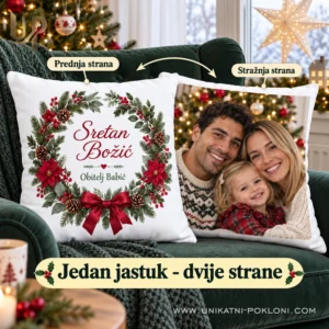 Jedan bijeli jastuk s božićnom čestitkom i obiteljskom fotografijom na fotelji uz prozor.