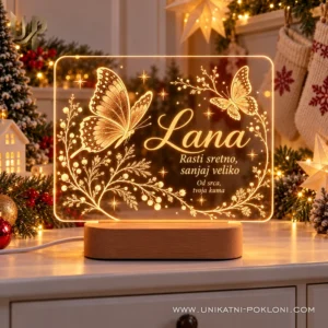 Personalizirana lampa s leptirima i imenom Lana u toplom žutom svjetlu uz božićne ukrase.